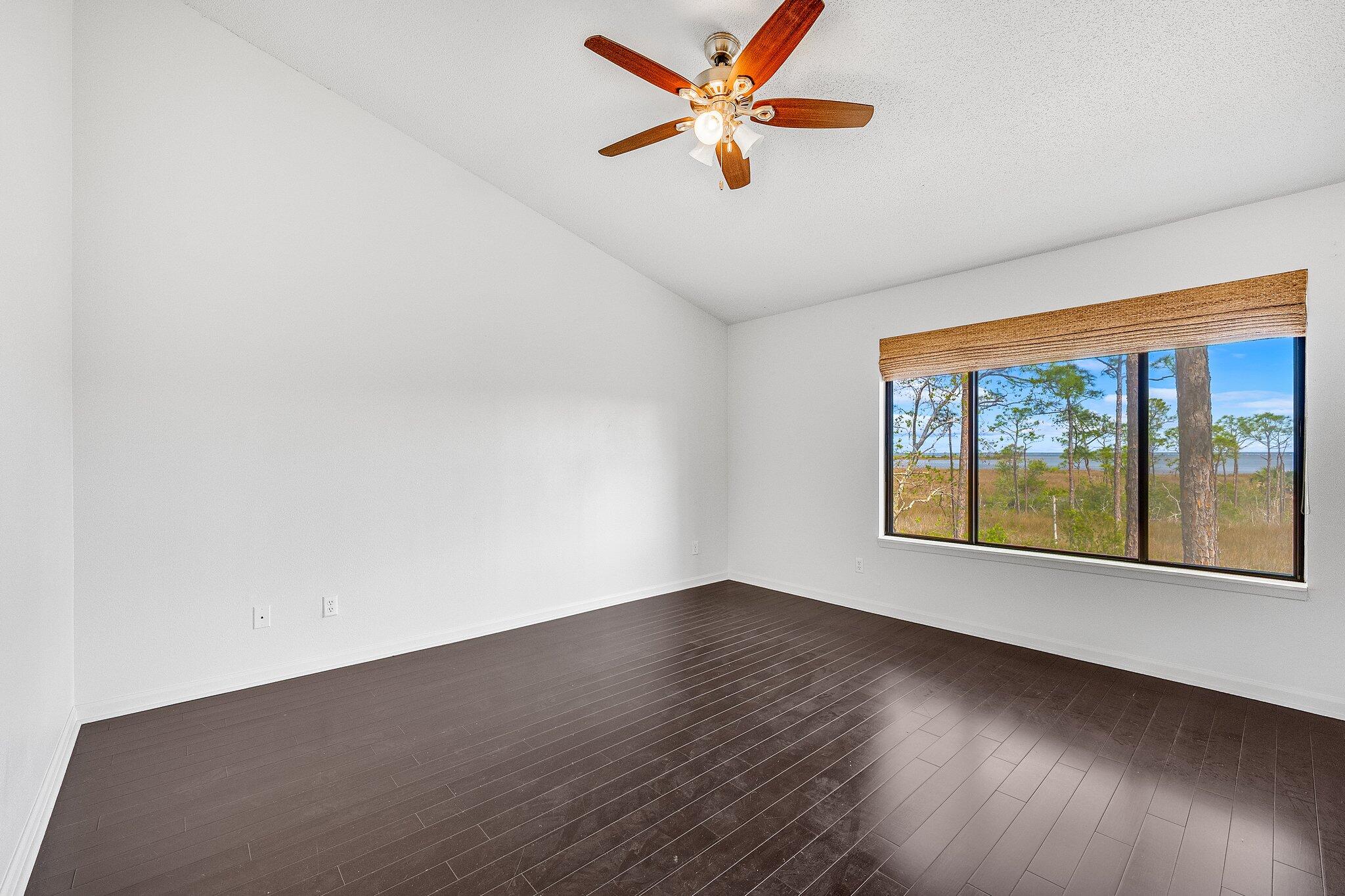 8983 Heron Walk Drive, Unit 8983 Miramar Beach, FL 32550 - Photo 14 of 57 an empty room with wooden floor fan and windows