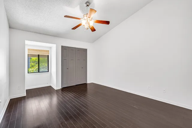 an empty room with wooden floor ceiling fan and window