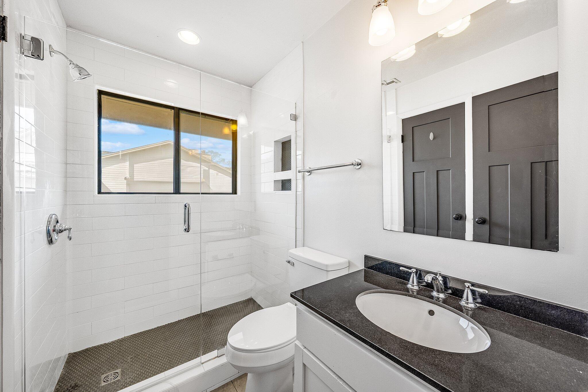 8983 Heron Walk Drive, Unit 8983 Miramar Beach, FL 32550 - Photo 25 of 57 a bathroom with a granite countertop sink toilet and mirror