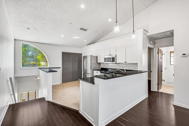 a kitchen with stainless steel appliances a stove a refrigerator a sink a oven with wooden floor