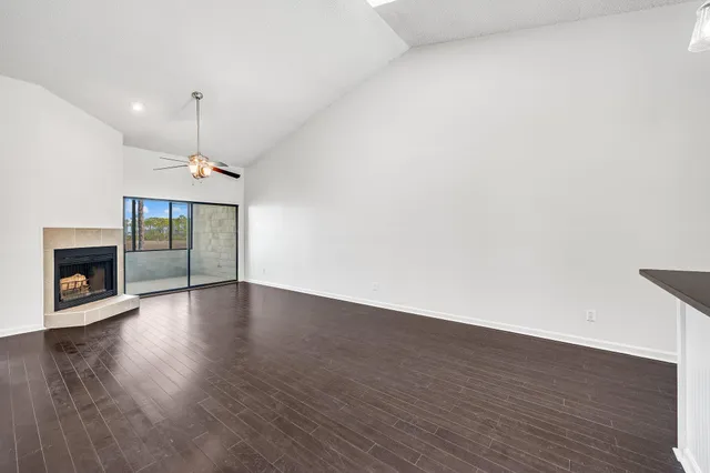 an empty room with wooden floor fireplace and a window