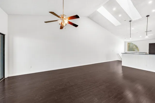 a view of an empty room with wooden floor and a ceiling fan