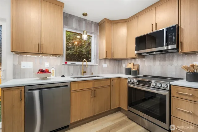 a kitchen with stainless steel appliances a stove a sink a microwave and cabinets