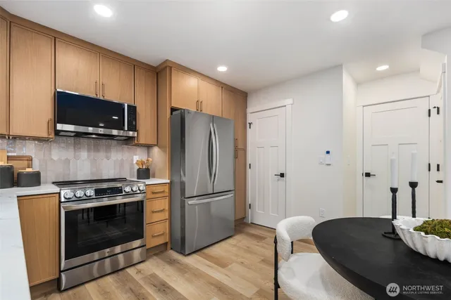 a kitchen with stainless steel appliances a stove a sink a microwave a refrigerator and cabinets