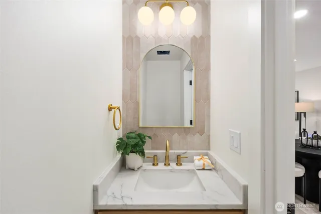a bathroom with a sink a mirror and a potted plant