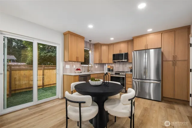 a kitchen with granite countertop stainless steel appliances a refrigerator a stove a dining table and chairs