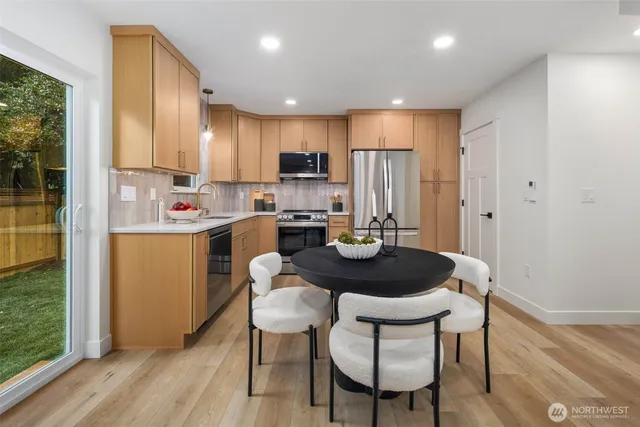 a kitchen with a dining table chairs and refrigerator