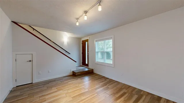 a view of an empty room with wooden floor and a window