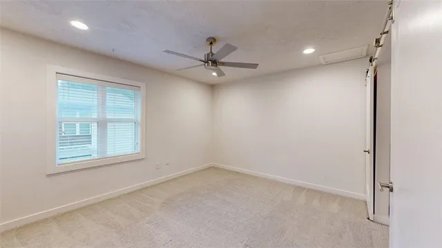 an empty room with a window and a fan