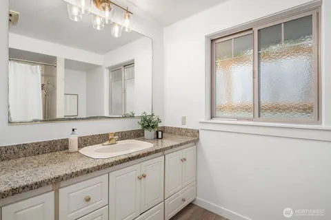 a bathroom with a granite countertop sink mirror and cabinets