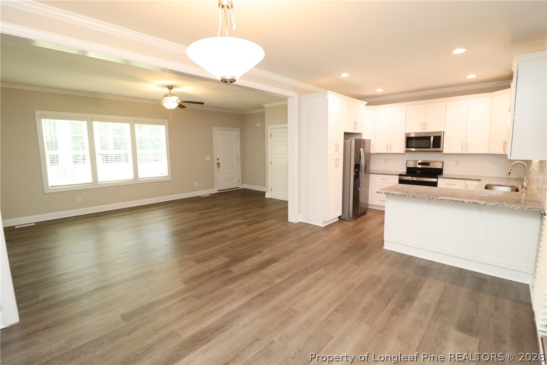 8424 Rhodes Road Apex, NC 27539 - Photo 7 of 31 a view of a kitchen with kitchen island wooden floors appliances and cabinets