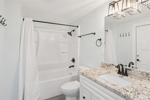 a bathroom with a granite countertop sink a toilet and a mirror