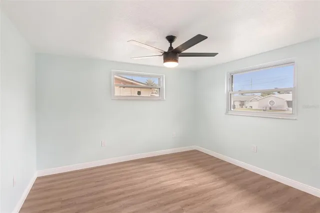 an empty room with wooden floor and ceiling fan