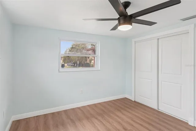 an empty room with a ceiling fan and wooden floor
