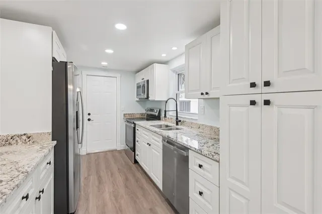 a kitchen with granite countertop white cabinets and white appliances