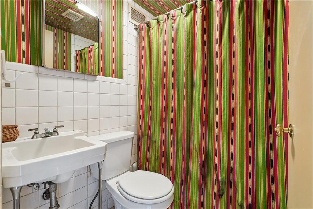 5048 Fifth Avenue, Unit 101 Pittsburgh, PA 15232 - Photo 16 of 24 a bathroom with a sink a toilet and shower curtain
