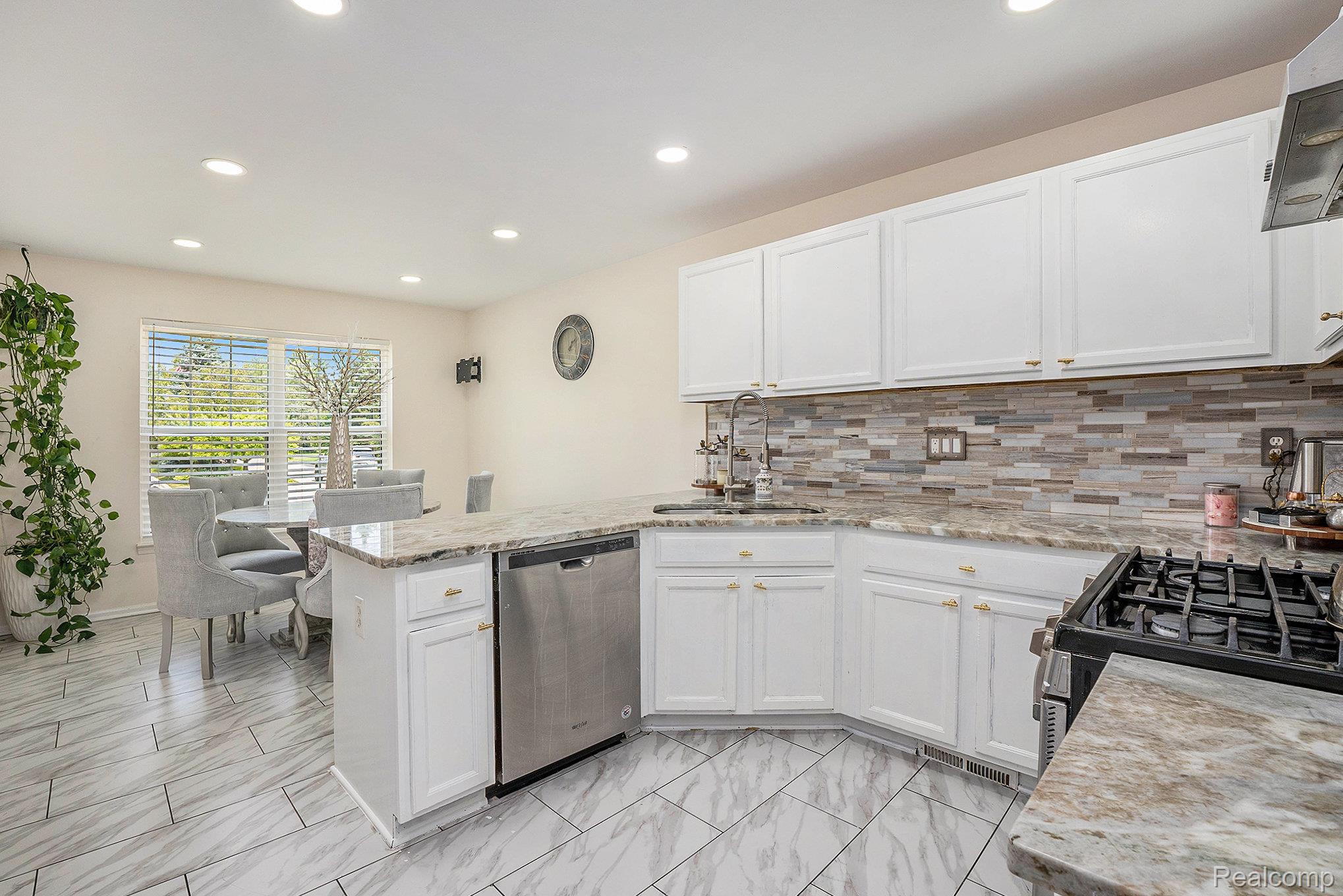 5477 Victory Circle Sterling Heights, MI 48310 - Photo 15 of 32 Modern kitchen featuring white cabinetry, granite countertops, and a tiled backsplash