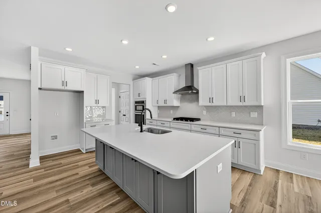 a kitchen with kitchen island a sink a stove and white cabinets with wooden floor