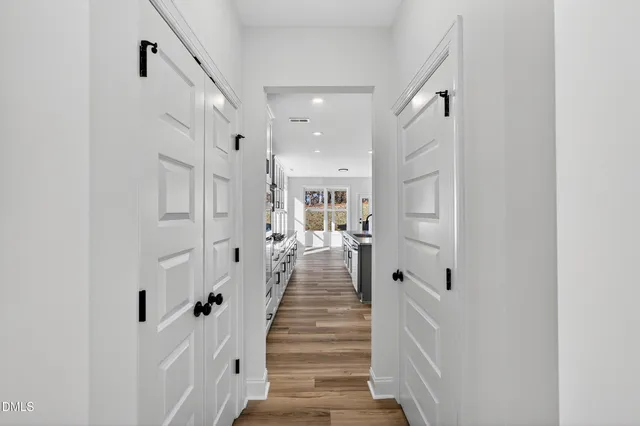 a view of a hallway with white walls and wooden floor