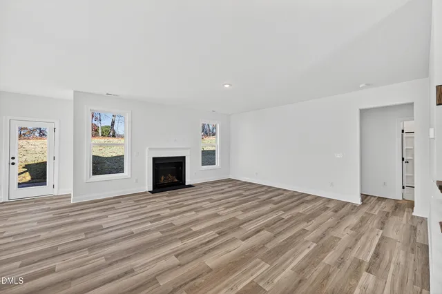 a view of empty room with wooden floor and fireplace