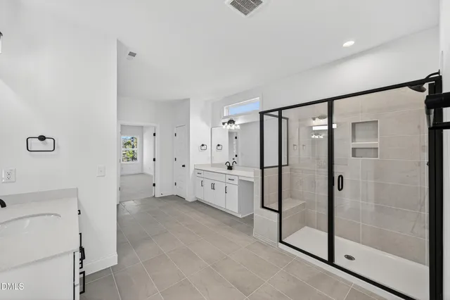a large white bathroom with a glass door shower a sink and a mirror