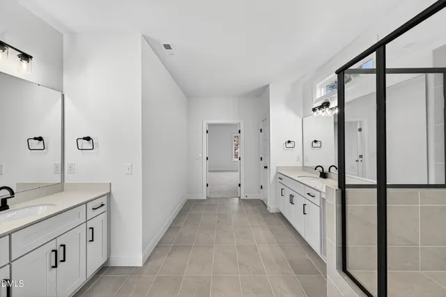 a spacious bathroom with a double vanity sink a mirror and a shower