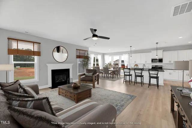 a living room with furniture a fireplace a clock and a large window