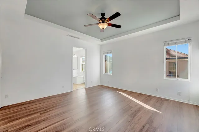 an empty room with wooden floor and ceiling fan