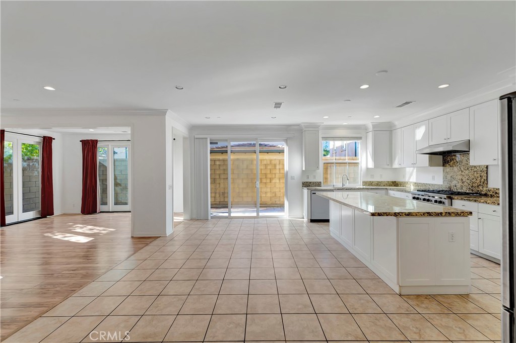 110 Mosswood Irvine, CA 92620 - Photo 4 of 38 a large white kitchen with stainless steel appliances granite countertop a large stove top oven and a refrigerator with a stove
