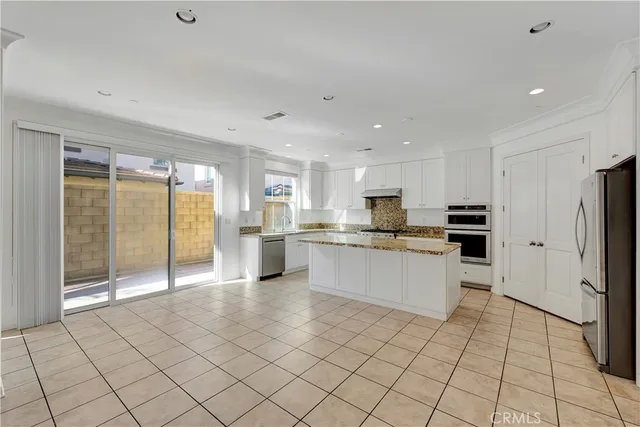 a large white kitchen with stainless steel appliances granite countertop a refrigerator and a stove top oven