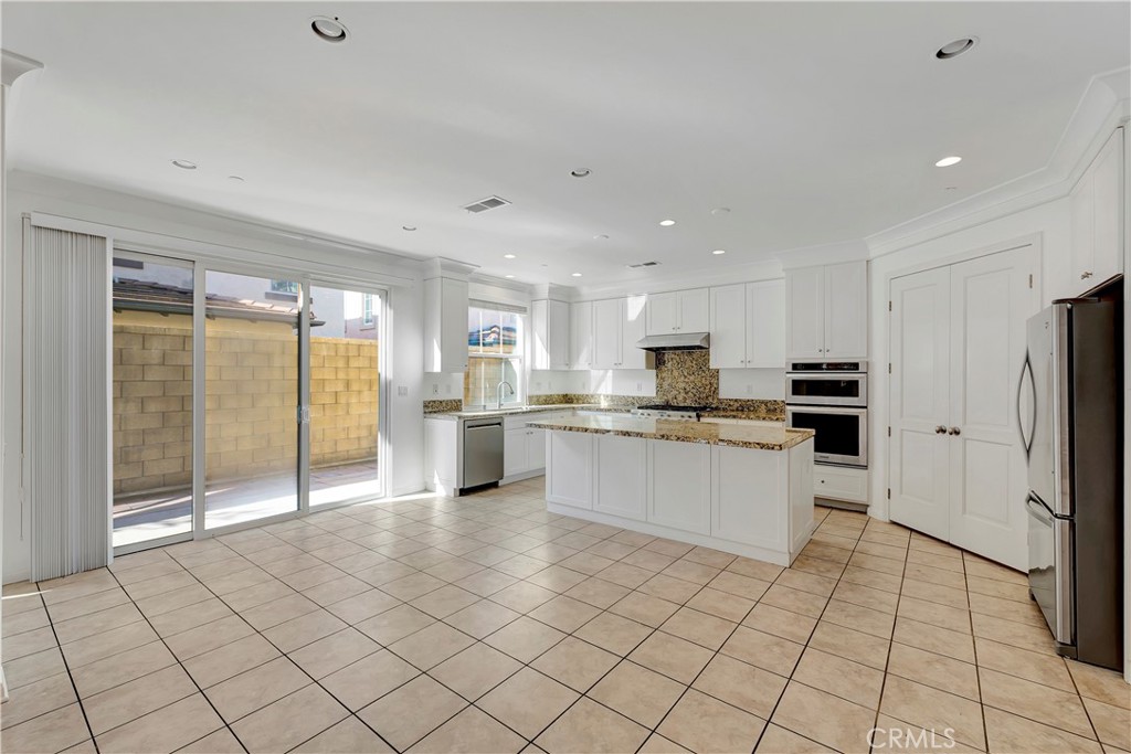 110 Mosswood Irvine, CA 92620 - Photo 8 of 38 a large white kitchen with stainless steel appliances granite countertop a refrigerator and a stove top oven