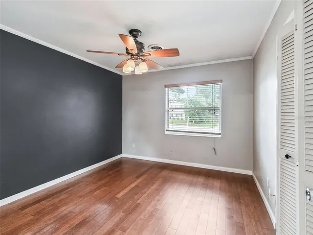 an empty room with wooden floor fan and windows