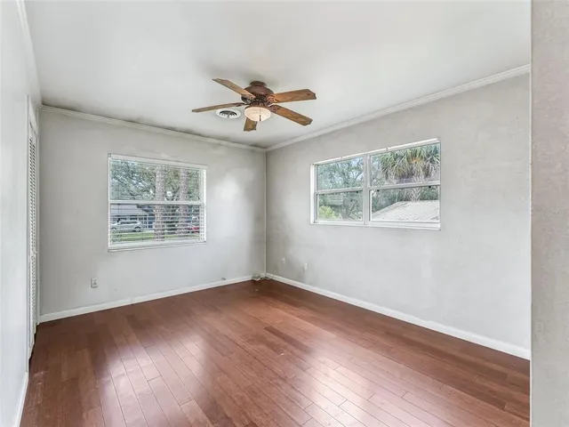 a view of an empty room with wooden floor and a window