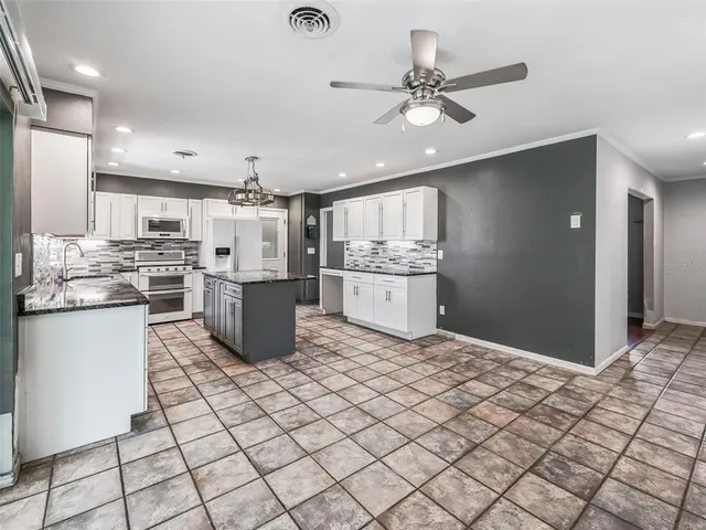 a kitchen with stainless steel appliances kitchen island granite countertop a refrigerator and a stove top oven