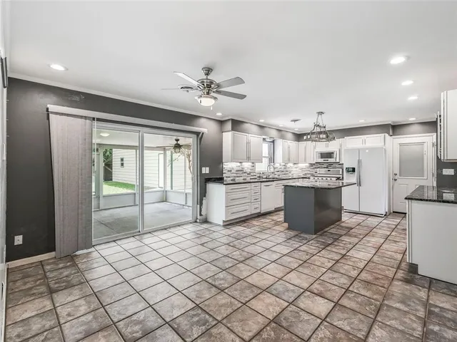 a large white kitchen with a stove a sink dishwasher and a refrigerator with wooden floor