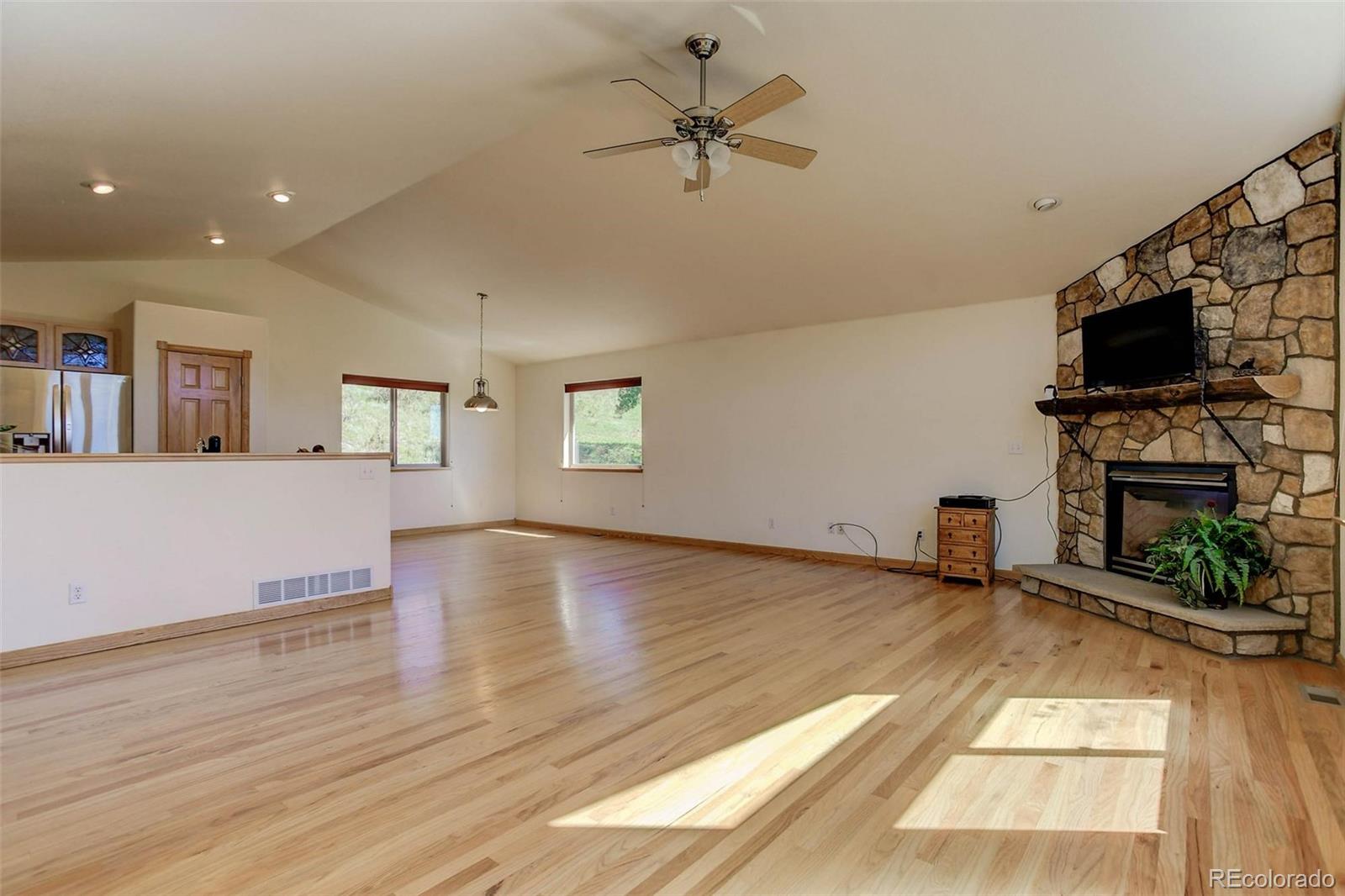 29 Pine Trail Bailey, CO 80421 - Photo 6 of 30 a view of a livingroom with a fireplace a ceiling fan and windows