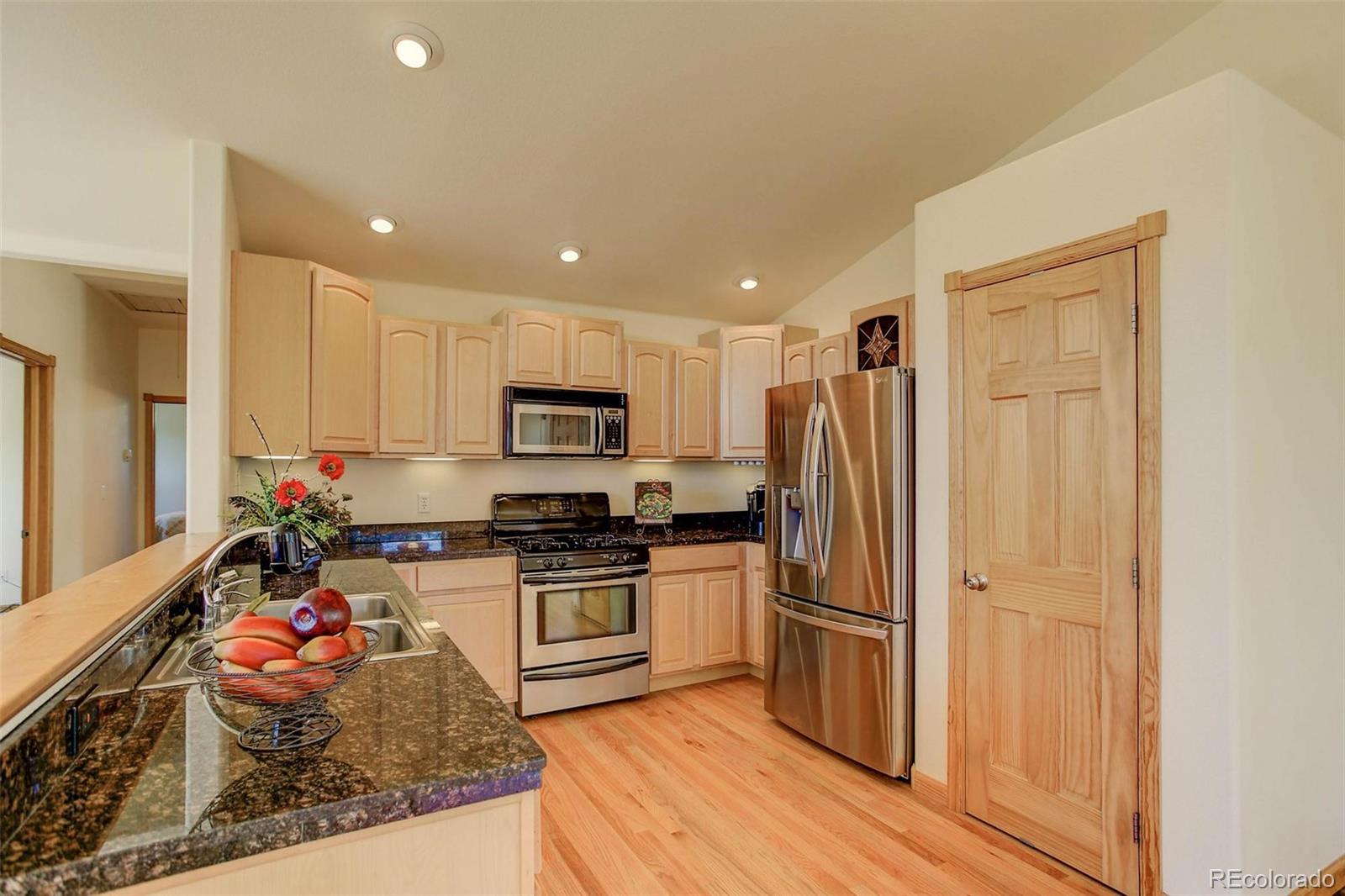 29 Pine Trail Bailey, CO 80421 - Photo 9 of 30 a kitchen with stainless steel appliances granite countertop a stove top oven a refrigerator and white cabinets with wooden floor