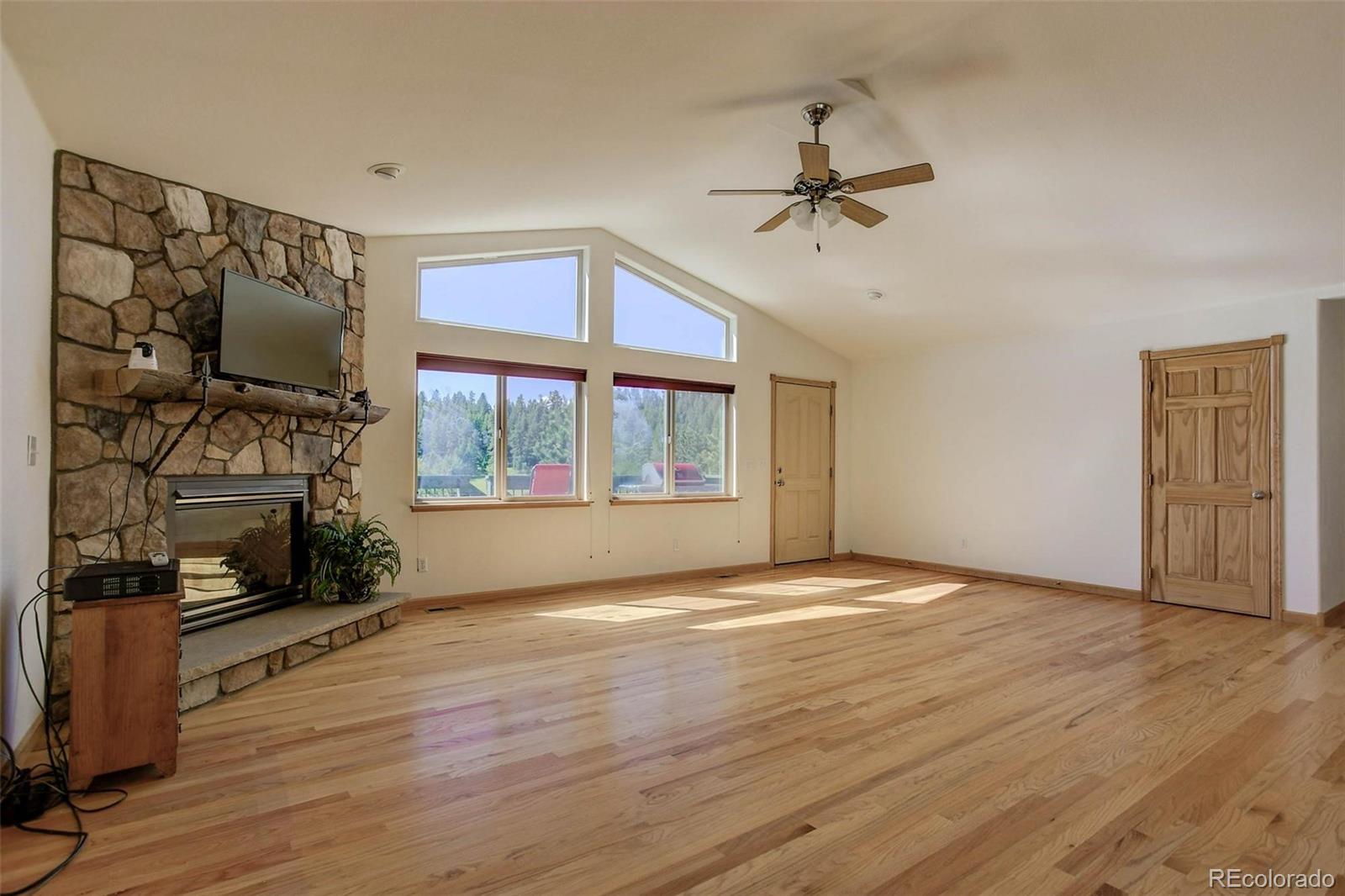 29 Pine Trail Bailey, CO 80421 - Photo 10 of 30 a view of an empty room with wooden floor fireplace and a window