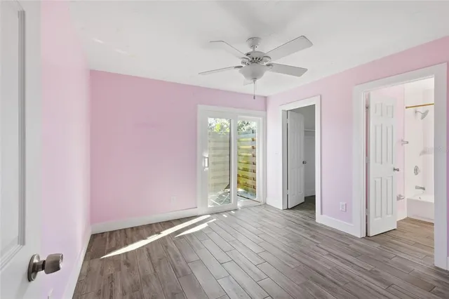 an empty room with wooden floor fan and windows