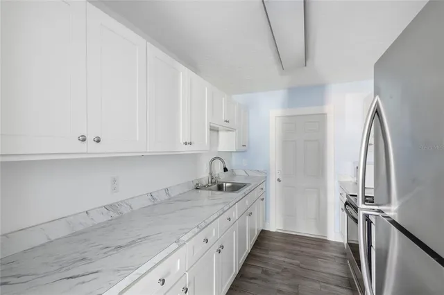 a kitchen with granite countertop a sink and a refrigerator