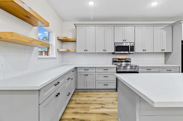 a kitchen with stainless steel appliances granite countertop a sink a stove a refrigerator and island with wooden floor