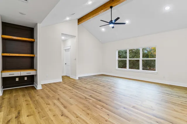 a view of an empty room with a window and wooden floor