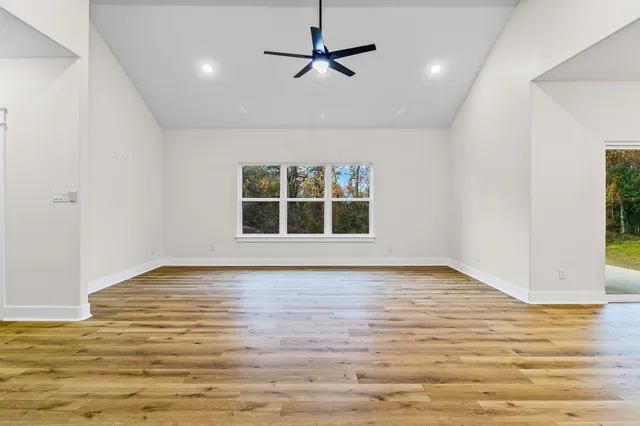 a view of an empty room with window and wooden floor