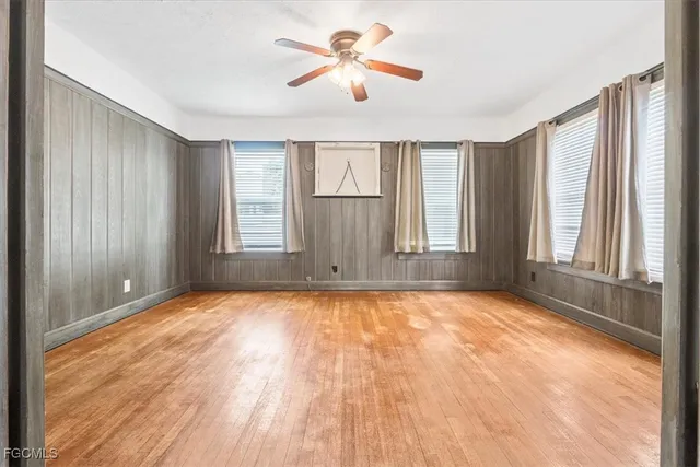 an empty room with windows and ceiling fan