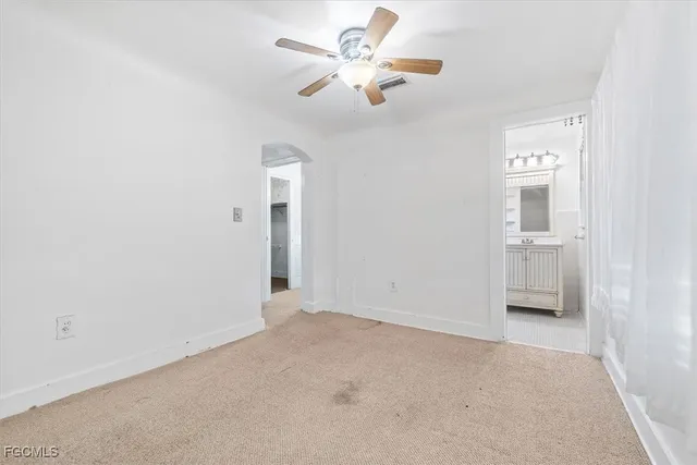 an empty room with chandelier fan and windows