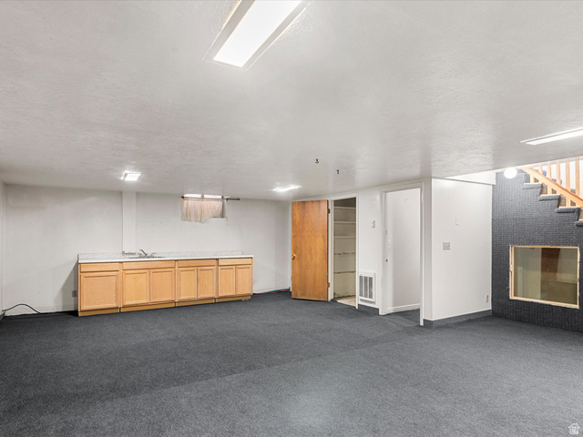 15680 North Beaver Dam Road Collinston, UT 84306 - Photo 29 of 49 Spacious room featuring gray carpeting, a built-in wet bar with wood cabinetry and a laminate countertop, and overhead fluorescent lighting