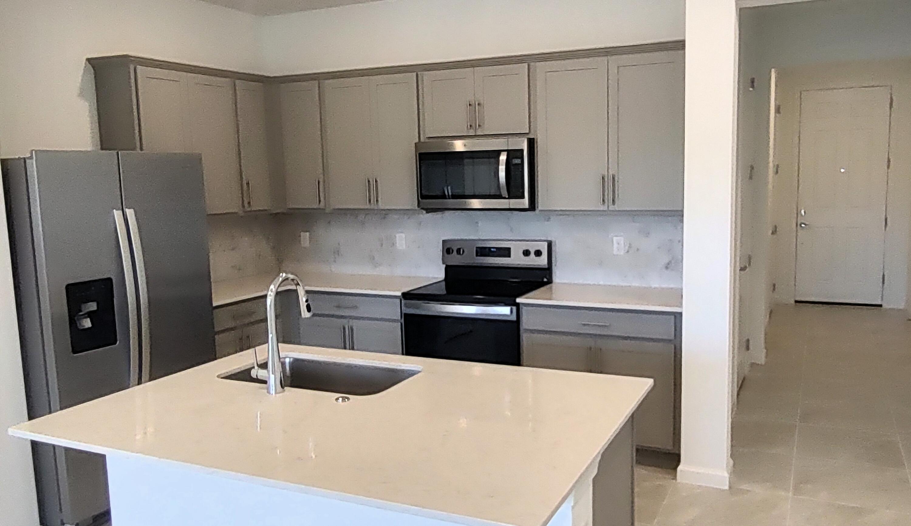 7783 Southwest Bentley Lane Stuart, FL 34997 - Photo 6 of 34 a kitchen with stainless steel appliances a refrigerator a stove a microwave and sink