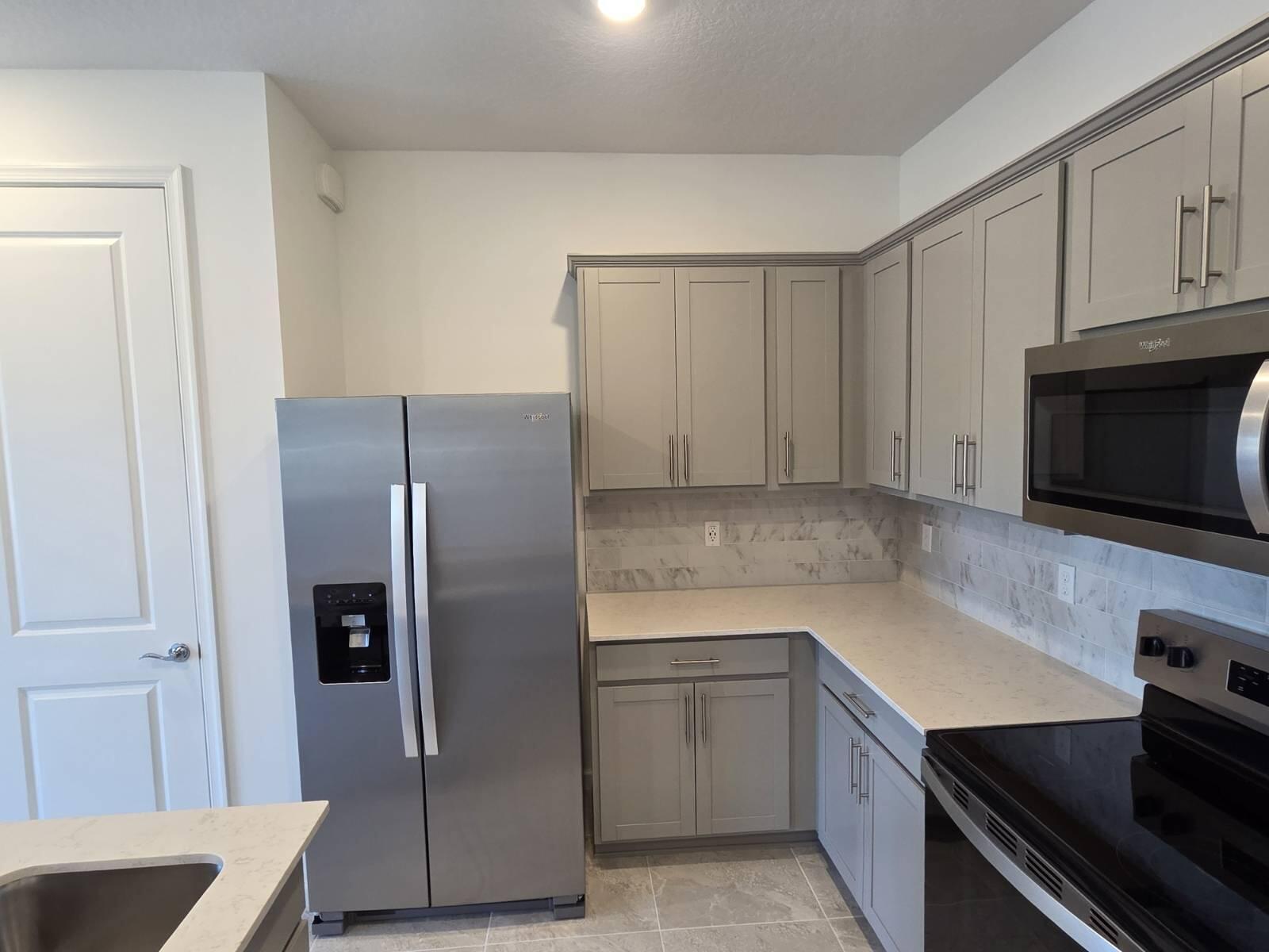 7783 Southwest Bentley Lane Stuart, FL 34997 - Photo 7 of 34 a kitchen with a refrigerator stove and cabinets