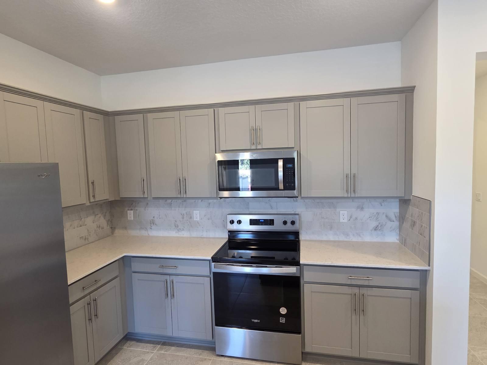 7783 Southwest Bentley Lane Stuart, FL 34997 - Photo 8 of 34 a kitchen with stainless steel appliances granite countertop a sink stove and microwave