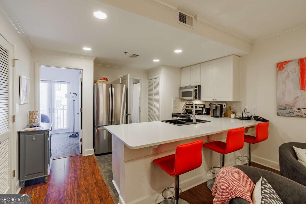 250 West Broad Street, Unit 714 Athens, GA 30601 - Photo 6 of 21 a kitchen with stainless steel appliances granite countertop a dining table chairs sink refrigerator and microwave